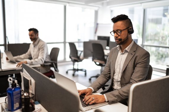 A guy taking calls in front of a laptop computer