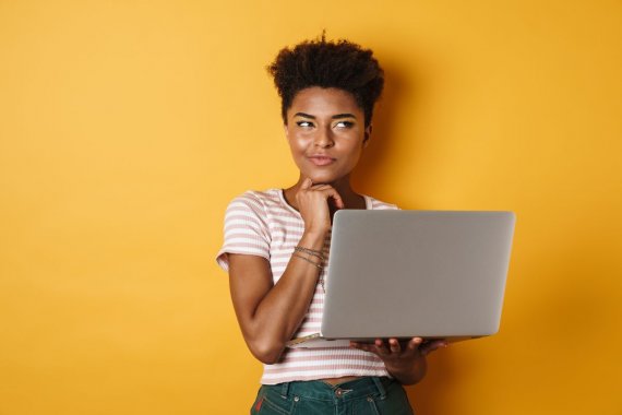 a girl holding a laptop on her left hand and acting like she is thinking something