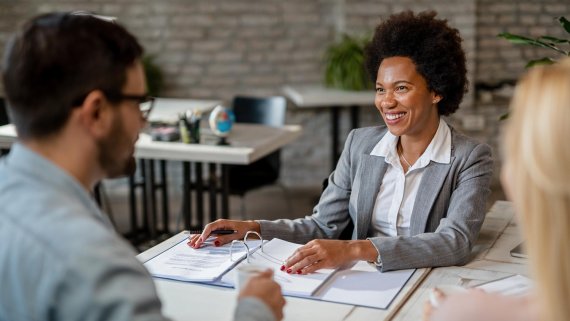 A man and a woman are seated at a table, looking at documents and possibly discussing business or financial matters.