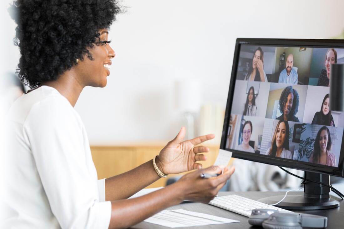 A person participating in a virtual meeting on Microsoft Teams, with multiple video feeds visible on the monitor