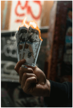 A person's hand holding burning currency