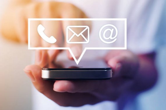 A hand holding a smartphone with floating icons representing phone, email, and website/social media, symbolizing contact methods or communication.